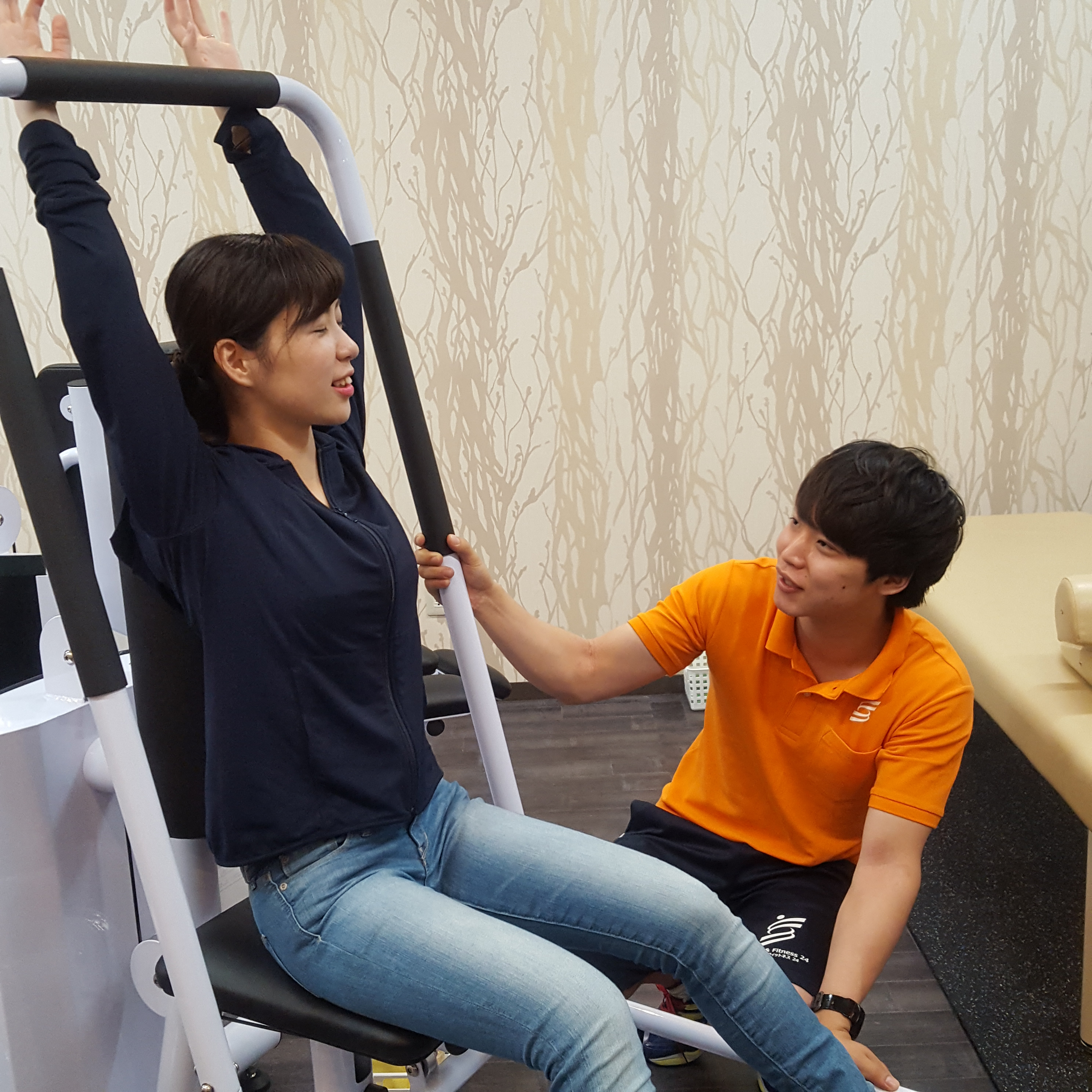 東十条駅から徒歩5分のパーソナルトレーニングに特化したスポーツジムのストレッチ&フィットネス24十条店のスタッフがストレッチマシンを指導している画像